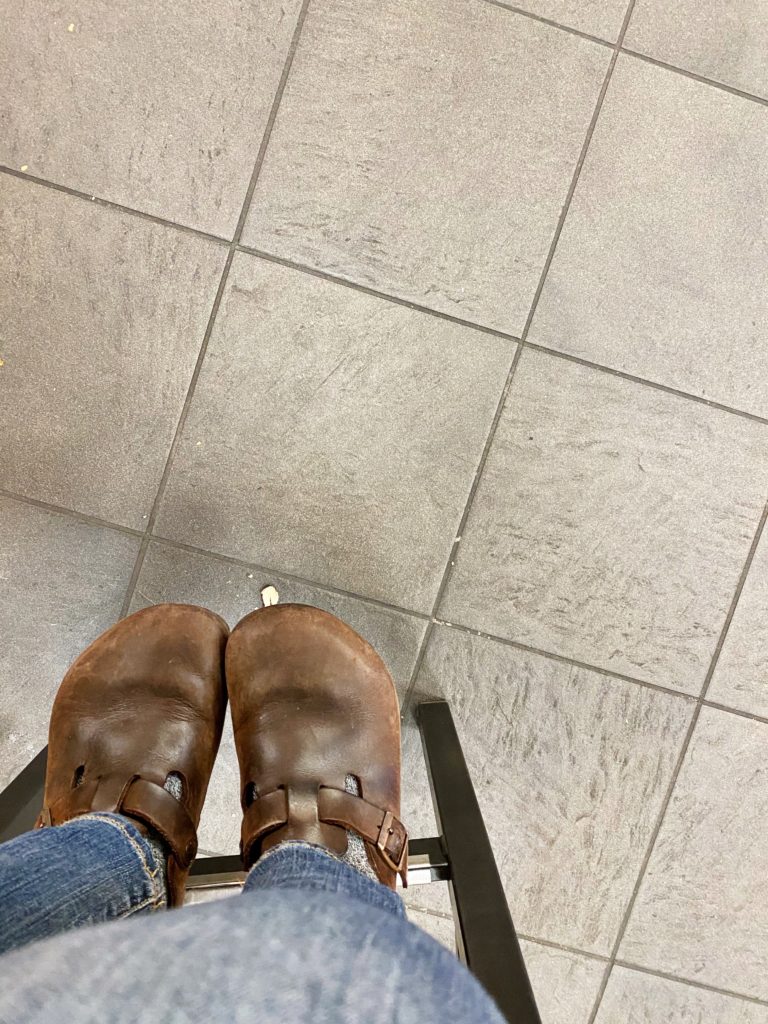 photo of feet in clogs hanging off support beam on chair