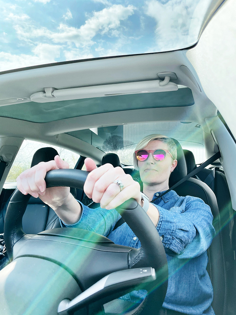 Author driving a car with hands on the steering wheel in the foreground