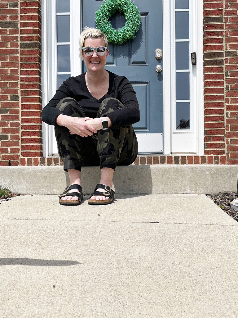 Author sitting on step in front of house wearing sunglasses 