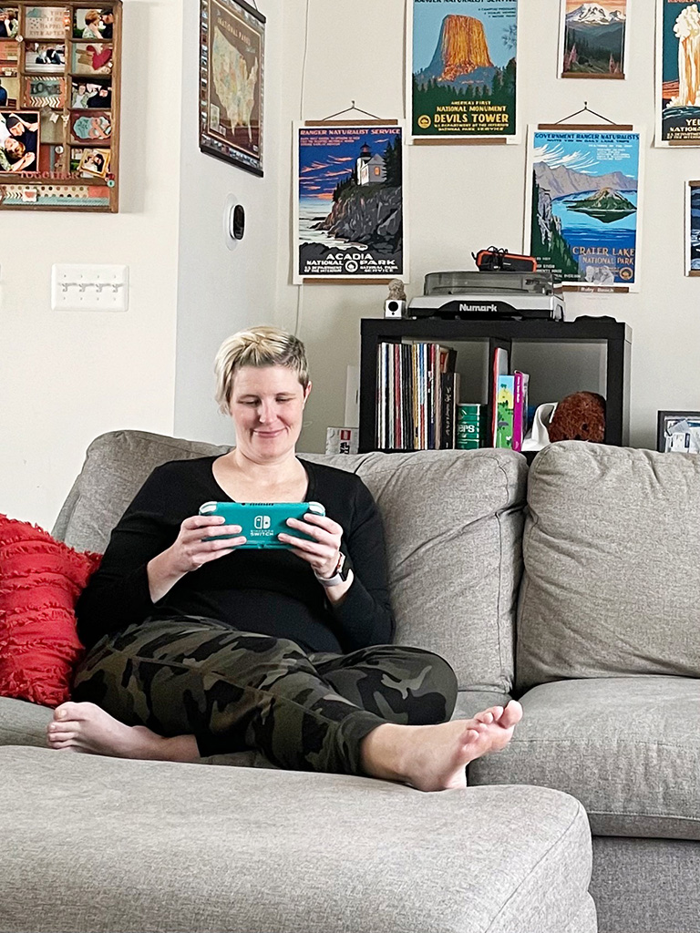 Author sitting on couch holding a Nintendo Switch