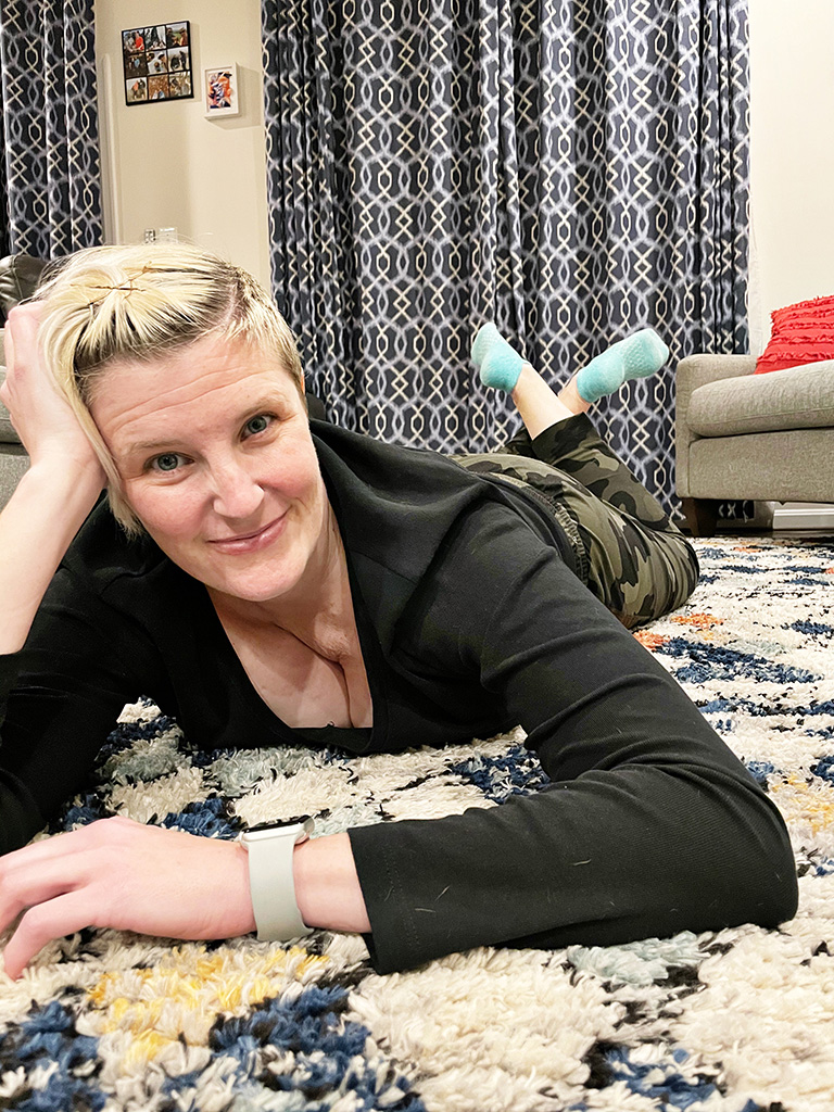 Author laying on floor with head propped up in hand and feet raised and crossed at the ankles